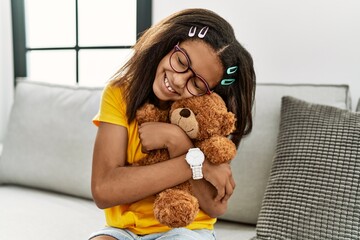African american girl smiling confident hugging teddy bear at home - Powered by Adobe