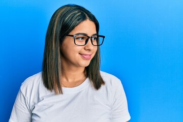 Young latin woman wearing casual clothes and glasses looking to side, relax profile pose with natural face and confident smile.