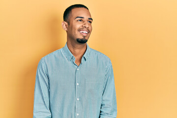 Young african american man wearing casual clothes looking away to side with smile on face, natural expression. laughing confident.