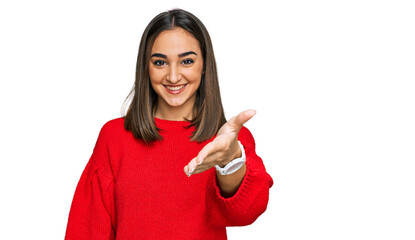 Beautiful brunette woman wearing casual winter sweater smiling friendly offering handshake as greeting and welcoming. successful business.