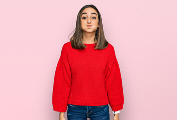 Beautiful brunette woman wearing casual winter sweater puffing cheeks with funny face. mouth inflated with air, crazy expression.