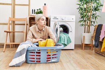 Young caucasian woman leaning on laundry basket at laundry room