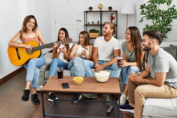 Group of young friends having party playing spanish guitar at home.
