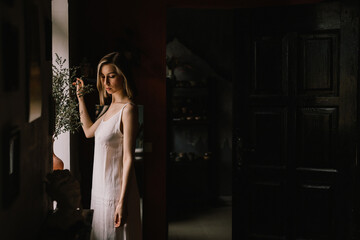 talented sculptor girl in light negligee stands in pottery workshop near large window. concept is beauty and art.