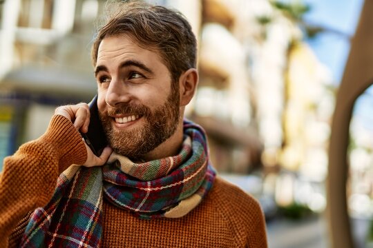 Caucasian man with beard having a conversation speaking on the phone outdoors on a sunny day