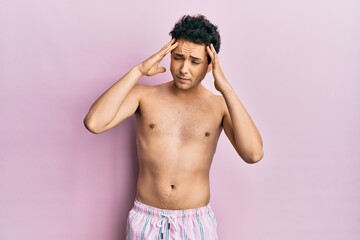 Fototapeta premium Young handsome man wearing swimwear shirtless with hand on head for pain in head because stress. suffering migraine.