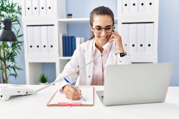 Young hispanic woman wearing doctor uniform working at clinic