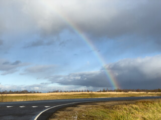 Naklejka na ściany i meble Rainbow over straight road with markings. 