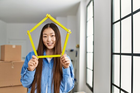 Young chinese girl smiling happy holding house project standing at new home