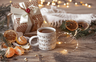 Christmas composition with a festive cup and tangerines on a blurred background.