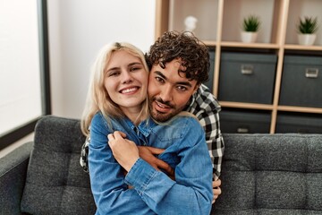 Young couple sitting on the sofa hugging at home.