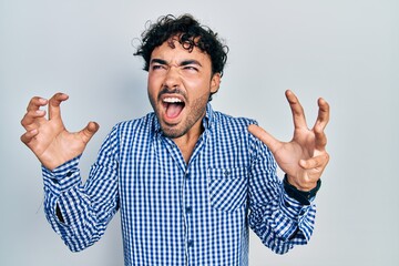 Fototapeta premium Young hispanic man wearing casual clothes crazy and mad shouting and yelling with aggressive expression and arms raised. frustration concept.