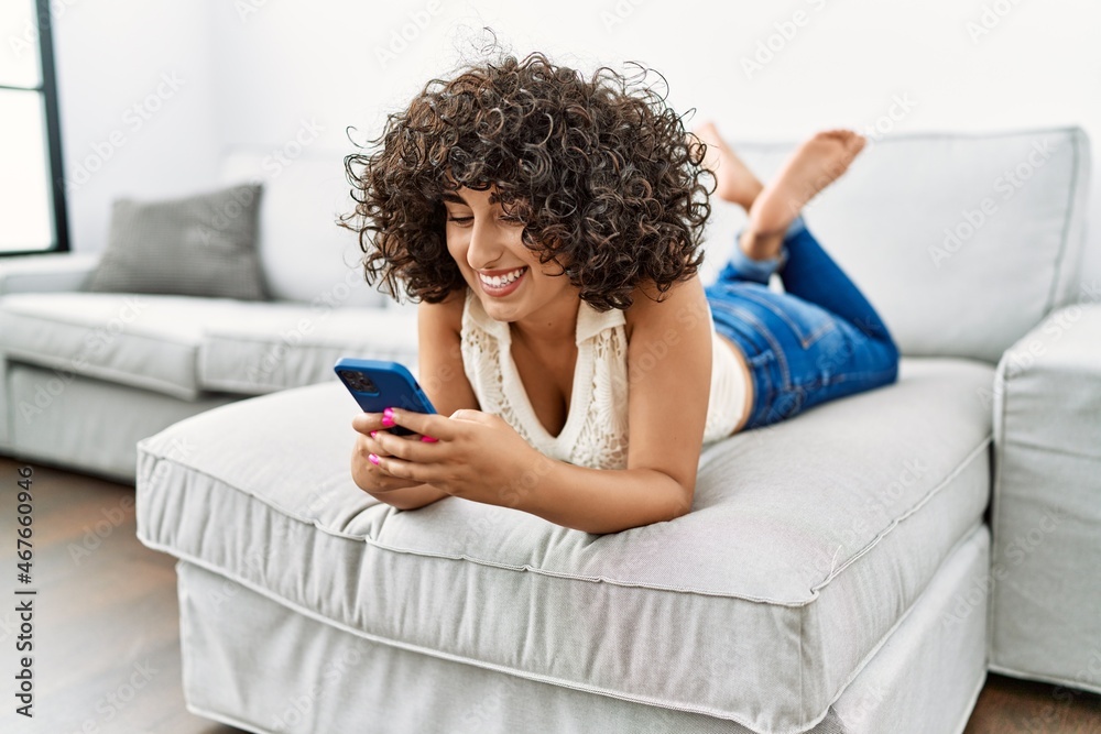 Wall mural Young middle east woman smiling confident using smartphone at home