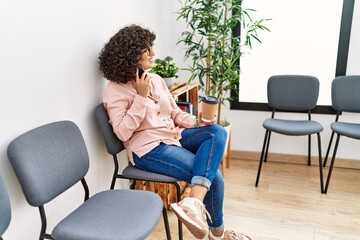 Young middle east woman talking on the smartphone drinking coffee at waiting room