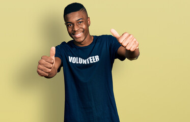 Young african american man wearing volunteer t shirt approving doing positive gesture with hand, thumbs up smiling and happy for success. winner gesture.