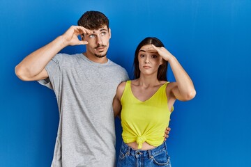 Young hispanic couple standing together over blue background worried and stressed about a problem with hand on forehead, nervous and anxious for crisis