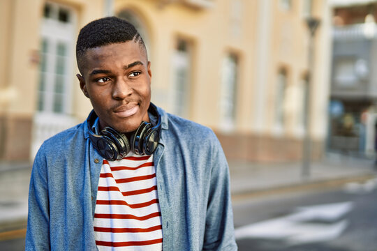 Young african american man with serious expression using headphones at the city.