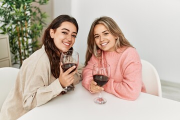 Young couple smiling happy toasting with red wine glass at home.