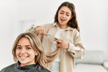 Fototapeta premium Young woman cutting hair to her girlfriend at home.