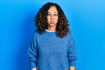 Middle age hispanic woman wearing casual clothes puffing cheeks with funny face. mouth inflated with air, crazy expression.