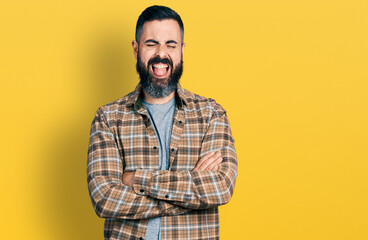 Obraz premium Hispanic man with beard with arms crossed gesture sticking tongue out happy with funny expression.