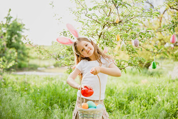 Baby with basket full of colorful eggs. Easter egg hunt.