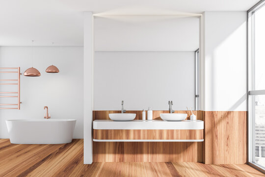 Bright bathroom interior with bathtub, two sinks, mirror