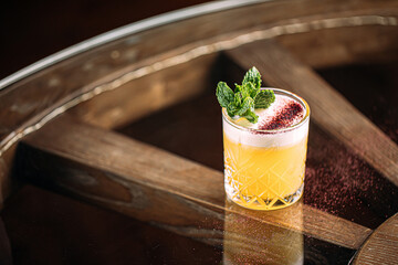 Side view on yellow whisky sour cocktail garnished with mint