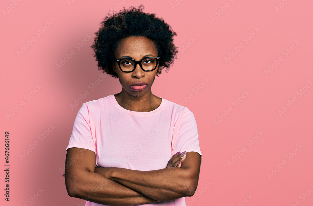 Poster African american woman with afro hair wearing casual clothes and glasses skeptic and nervous, disapproving expression on face with crossed arms. negative person.