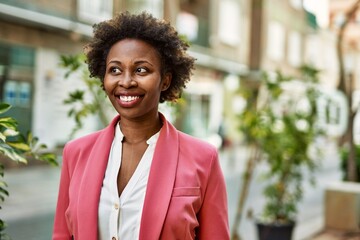 Beautiful business african american woman with afro hair smiling happy and confident outdoors at the city