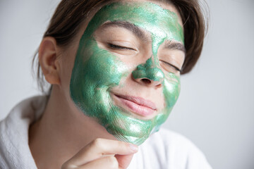 Attractive young woman with a green cosmetic mask on her face.