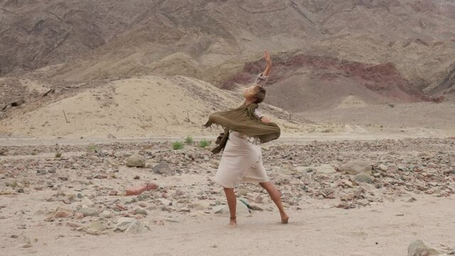 Woman dance of tenderness in the desert. Young beautiful girl slowly dancing on the sand. Slow motion shot