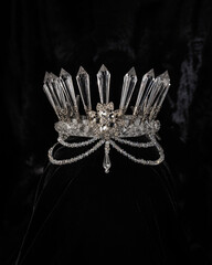 beautiful silver crown with crystals on a black shiny background, accessory headdress, close-up