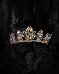beautiful silver crown with a yellow stone for a beauty pageant on a black background, accessory headdress, close-up © mira_y