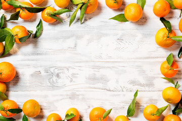 Fresh mandarin fruits with leaves on white wooden table.  top view