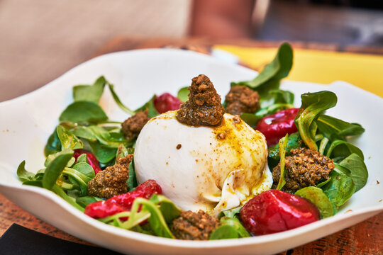 Beautiful burrata cheese with pesto on lambs lettuce salad image