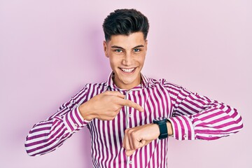Young hispanic man wearing casual clothes in hurry pointing to watch time, impatience, upset and...