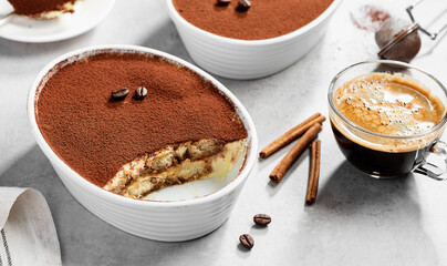 Classic Italian Dessert Tiramisu topped with cocoa in a ceramic dish. Light gray background.	