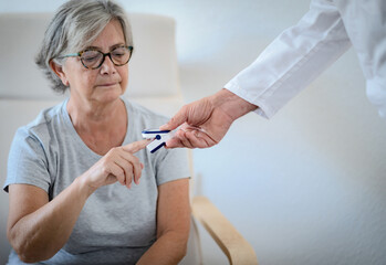 Doctor measure blood oxygen saturation in a senior patient woman