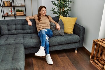 Middle age caucasian woman smiling happy sitting on the sofa at home.