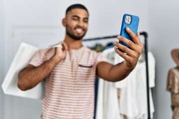 Young arab man make selfie by the smartphone holding shopping bags at clothing store
