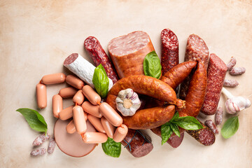 Set of different types of sausages, salami and smoked meat with basil and spices on light...