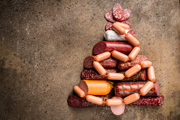 Christmas tree from different types of sausages, salami and smoked meat with basil and spices on...