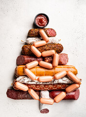 Christmas tree from different types of sausages, salami and smoked meat with basil and spices on white background. Top view.