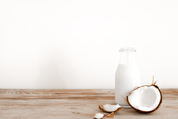 Fresh coconut milk in glass bottle, vegan non dairy healthy drink. Wooden table, close-up. Free space for text, copy space.