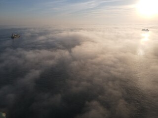 Obraz na płótnie Canvas aerial view in foggy day above sea with cargo ships