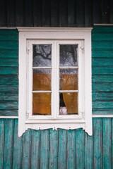 Vertical photo of the window of an old green wooden house in a village