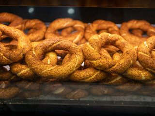 Simit - turkish bagels covered with sesame seeds are on the shop window behind the glass.