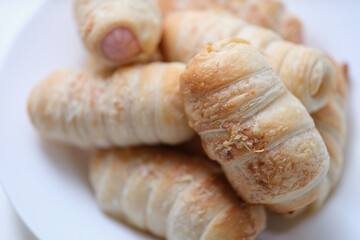 Hot delicious sausages in dough on a plate, puff bun
