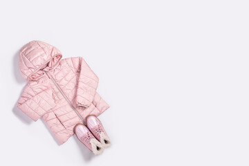 Children's jacket and boots for a girl on a white background. Top view, flat lay.